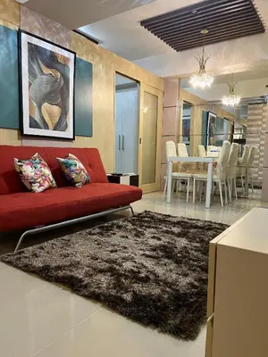 a living room with a red couch and a dining room at Sea Residences Mall of Asia Viann in Manila