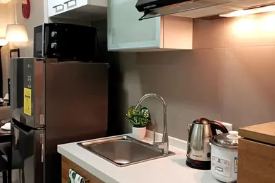 a kitchen counter with a sink and a refrigerator at Cozy Condo near BGC and Ortigas with free Gym & Pool in Manila