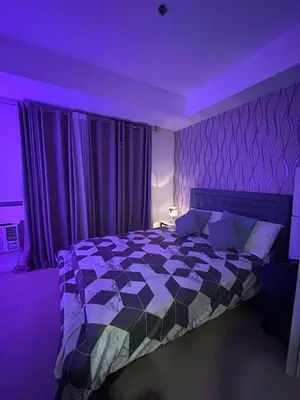 a bedroom with a bed with a purple lighting at 1BR Condotel in Azure Urban Resort Near NAIA #TRO3 in Manila