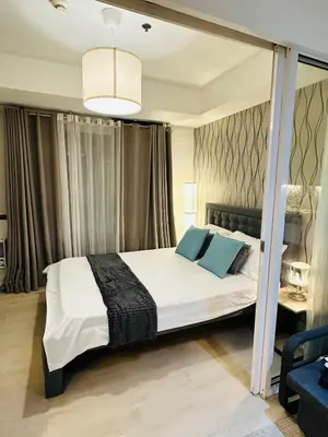 a bedroom with a large white bed with blue pillows at 1BR Condotel in Azure Urban Resort Near NAIA #TRO3 in Manila