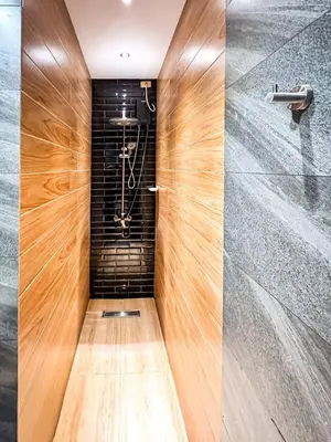 a walk in shower with a wood paneled wall at 4BR Townhouse w Garage, Peaceful near Restaurants in Manila