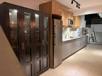 a kitchen with wooden cabinets and a refrigerator at 4BR Townhouse w Garage, Peaceful near Restaurants in Manila