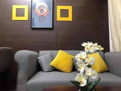 a living room with a gray couch and yellow pillows at Apartment in quezon city in Manila