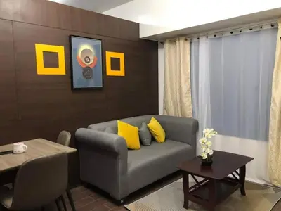 a living room with a gray couch and yellow pillows at Apartment in quezon city in Manila