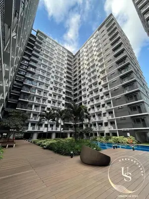a large apartment building with a clock in front of it at Mall of Asia condotel shore 3 residence in Manila