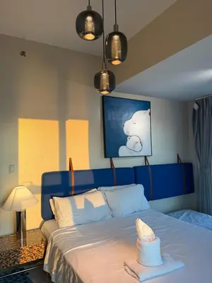 a bedroom with a blue bed with a hat on it at Modern 1BR with Balcony Facing Infinity Pool Manila Bay Sunset Near Airports OKADA Solaire MOA in Manila