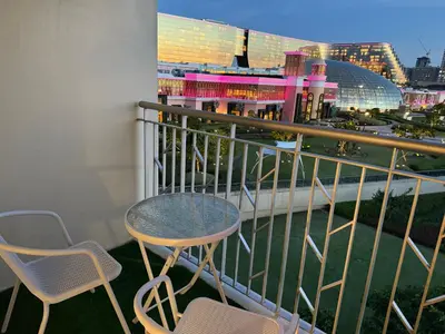 a balcony with two chairs and a table and a building at Modern 1BR with Balcony Facing Infinity Pool Manila Bay Sunset Near Airports OKADA Solaire MOA in Manila