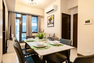 a dining room with a table and chairs in a room at Florence Mc Kinley Spacious 2 Bedroom, 2 balcony nr Mall, T3 airport in Manila