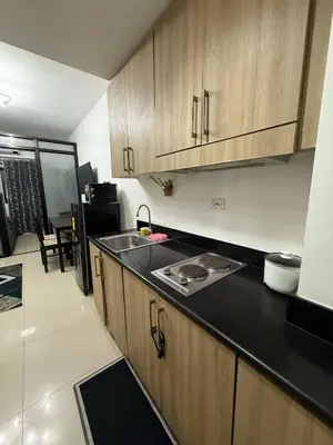 a kitchen with wooden cabinets and a black counter top at LJ&LUNA Staycation in Manila