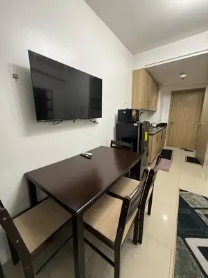 a dining room table with chairs and a television on a wall at LJ&LUNA Staycation in Manila