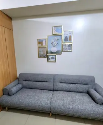 a couch against a white wall with pictures on it at 1BR with Netflix in Shell Residences Pasay in Manila
