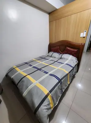 a bedroom with a bed with a wooden headboard at 1BR with Netflix in Shell Residences Pasay in Manila
