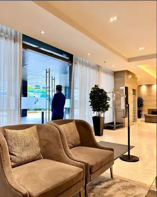 a living room with a couch and a man looking out the window at Apartment in Pasay, close to Mall Of Asia in Manila