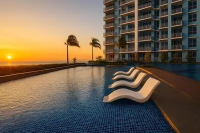 a hotel swimming pool with a white chair in front of a building at Lovely 1BR w Sunset near Solaire, Okada, Airport in Manila