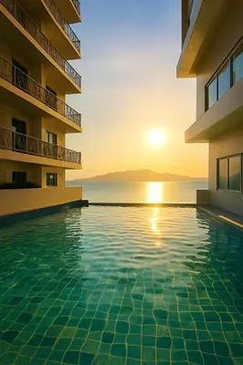 a swimming pool in front of a building with the sunset at Cozy 1BR near Solaire, Okada, Mall of Asia in Manila