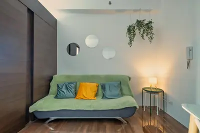 a green couch with two colorful pillows on it at Home with Best Sunset of Manila Bay and Sea view! in Manila