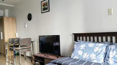 a bedroom with a bed and a flat screen tv at Furnished Studio in Knightsbridge Residences in Manila