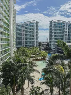a resort with a pool and palm trees and buildings at The Sandscape Suite in Manila
