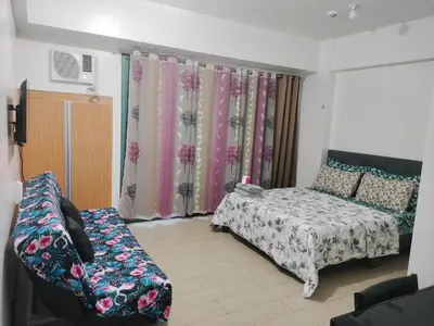 a bedroom with a bed and a couch and curtains at Rooms Near Airport-Rqui in Manila