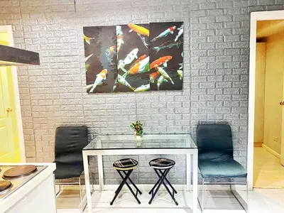 a table with two chairs and two paintings on a wall at 2bedroom azure beach 5 in Manila