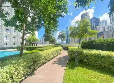 a walkway in a park with a city in the background at Cozy Makati 2BR in CBD Ayala area with games, KTV, and Amazing Pools! in Manila