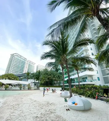 a beach with palm trees in front of a building at Azure Staycation by Leojen in Manila