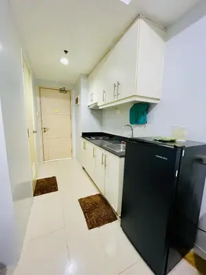 a kitchen with white cabinets and a black refrigerator at Simple Staycay in Manila
