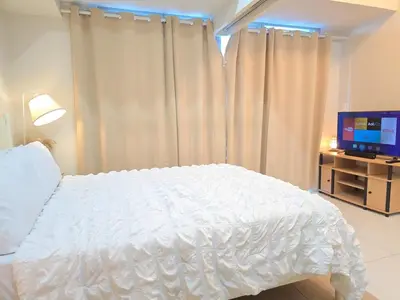 a bedroom with a white bed and a television at BGC Uptown Parksuites Cosy 1 Bedroom Suite with balcony 300MBPS wifi in Manila