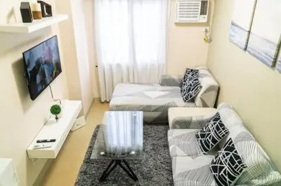 a living room with a couch and a bed at 1BR-unit in central BGC in Manila