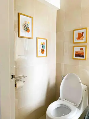 a bathroom with a toilet and paintings on the wall at 2BR Loft at Fort Victoria Condominium BGC in Manila