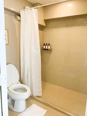 a bathroom with a white shower curtain and a toilet at 2BR Loft at Fort Victoria Condominium BGC in Manila