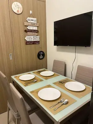 a room with a table with white plates and a tv at Staycation in Shore Residences, walking distance to MOA and near Manila Airport in Manila