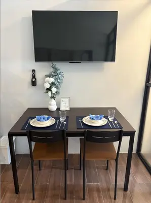 a black table with two chairs and a tv on a wall at Solace Haven in Manila