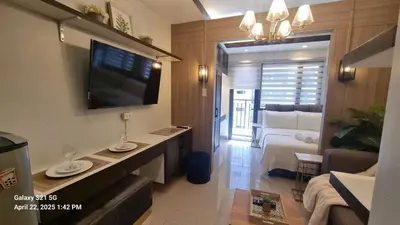 a living room with a television on a wall at Cozy new studio walk to Mall of Asia with balcony in Sampong