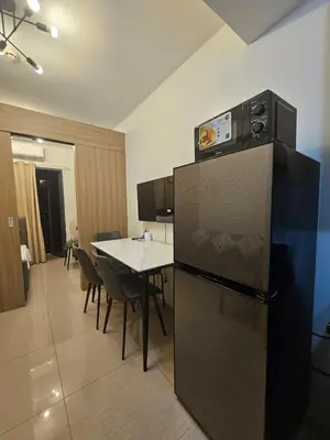 a kitchen with a refrigerator and a table with chairs at The Executive Suites at Shore 2 Residences in Manila
