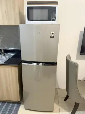 a refrigerator with a microwave on top of it at Larsie's Place in Manila