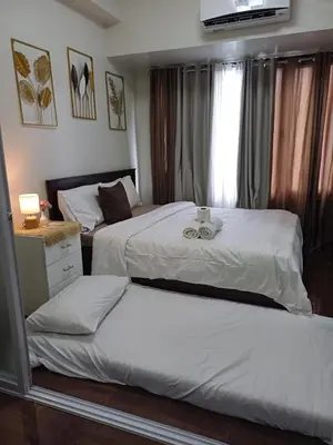 a bedroom with two beds and a window at CHIC 1 BR in Air Residences in Manila