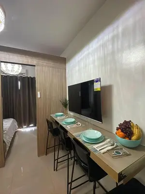 a long table with chairs and a television in a room at Modern Sanctuary Near - MOA in Manila
