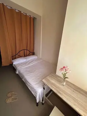 a small bed in a room with a table and flowers at Gen coZy Condo Stay by Victoria de Manila Tower in Manila