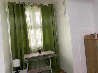 a green curtain with a table in front of a window at Gen coZy Condo Stay by Victoria de Manila Tower in Manila