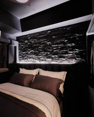 a bedroom with a bed with a stone wall at Luxury Condo in the heart of BGC in Manila