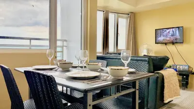 a dining room table with chairs and a table with wine glasses at SMDC BREEZE RESIDENCES Pasay near AIRPORT PICC CCP WORLD TRADE CENTER MOA AND STARCITY in Manila