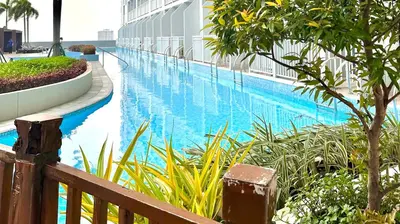a swimming pool next to a building with a resort at SMDC BREEZE RESIDENCES Pasay near AIRPORT PICC CCP WORLD TRADE CENTER MOA AND STARCITY in Manila