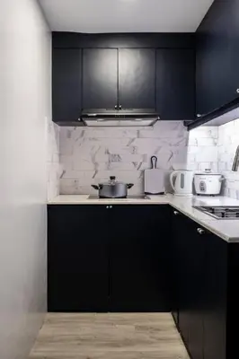 a kitchen with black cabinets and white appliances at BGC Designer Pad Near Shops Dining Nightlife in Manila