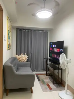 a living room with a chair and a television at The Residence Suite in Manila