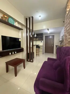 a living room with a purple couch and a tv at Relax Here! STUDIO TYPE in Manila