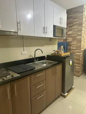a kitchen with wooden cabinets and a sink and a stove at Relax Here! STUDIO TYPE in Manila