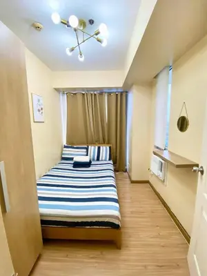 a bedroom with a bed with blue and white stripes at azure city view 2bedroom in Manila