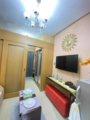 a living room with a television on the wall at 1528-1br-1bed-1sofa bed 1pull out pool view with balcony in Manila