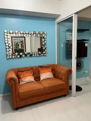 a brown couch in a living room with a mirror at 1 bedroom azure beachview 6 in Manila